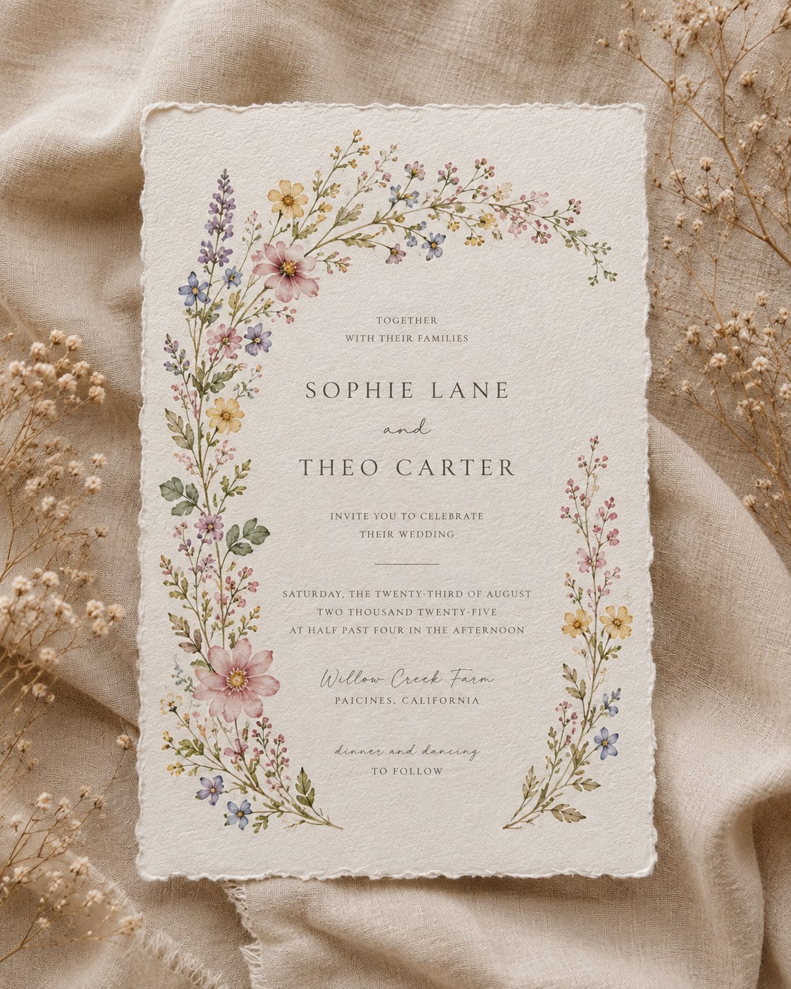 Boho wedding invitation with a wildflower wreath border in pastel meadow colors