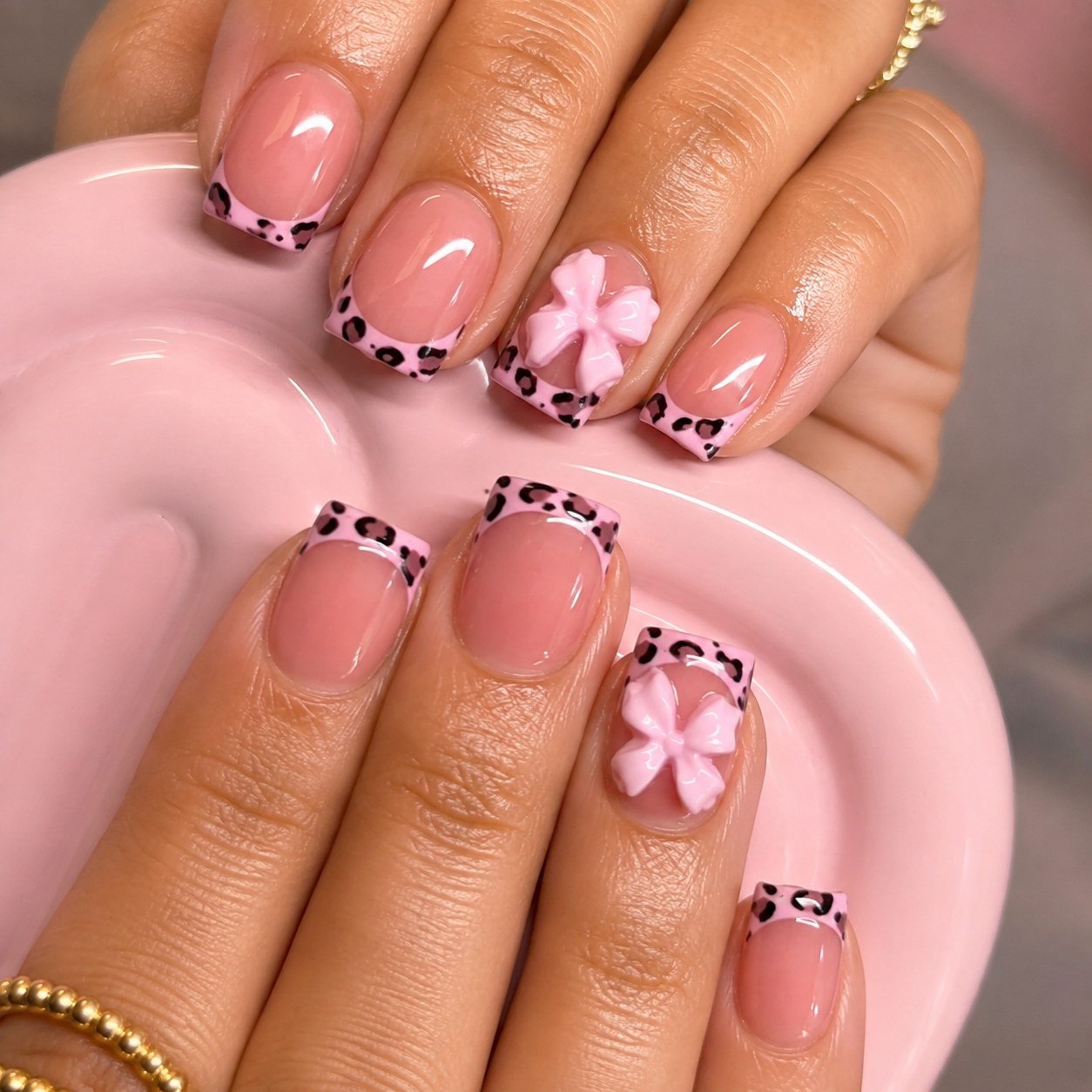 Square pink short nails with leopard French tips and a single 3D bow accent