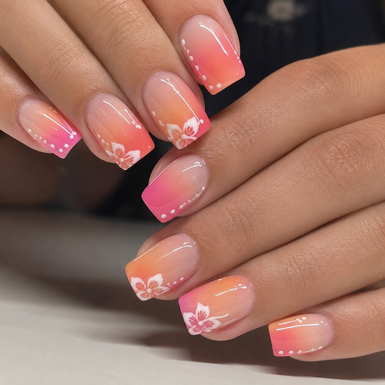 Short summer nails featuring a coral-to-yellow ombre with a white hibiscus flower design