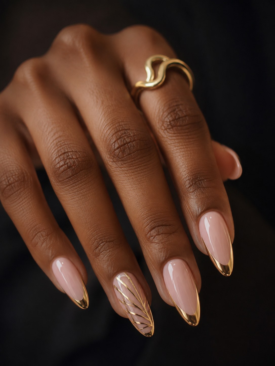 Almond nails with a gold chrome French tip and one leaf-art accent nail, a summer nail color for dark skin
