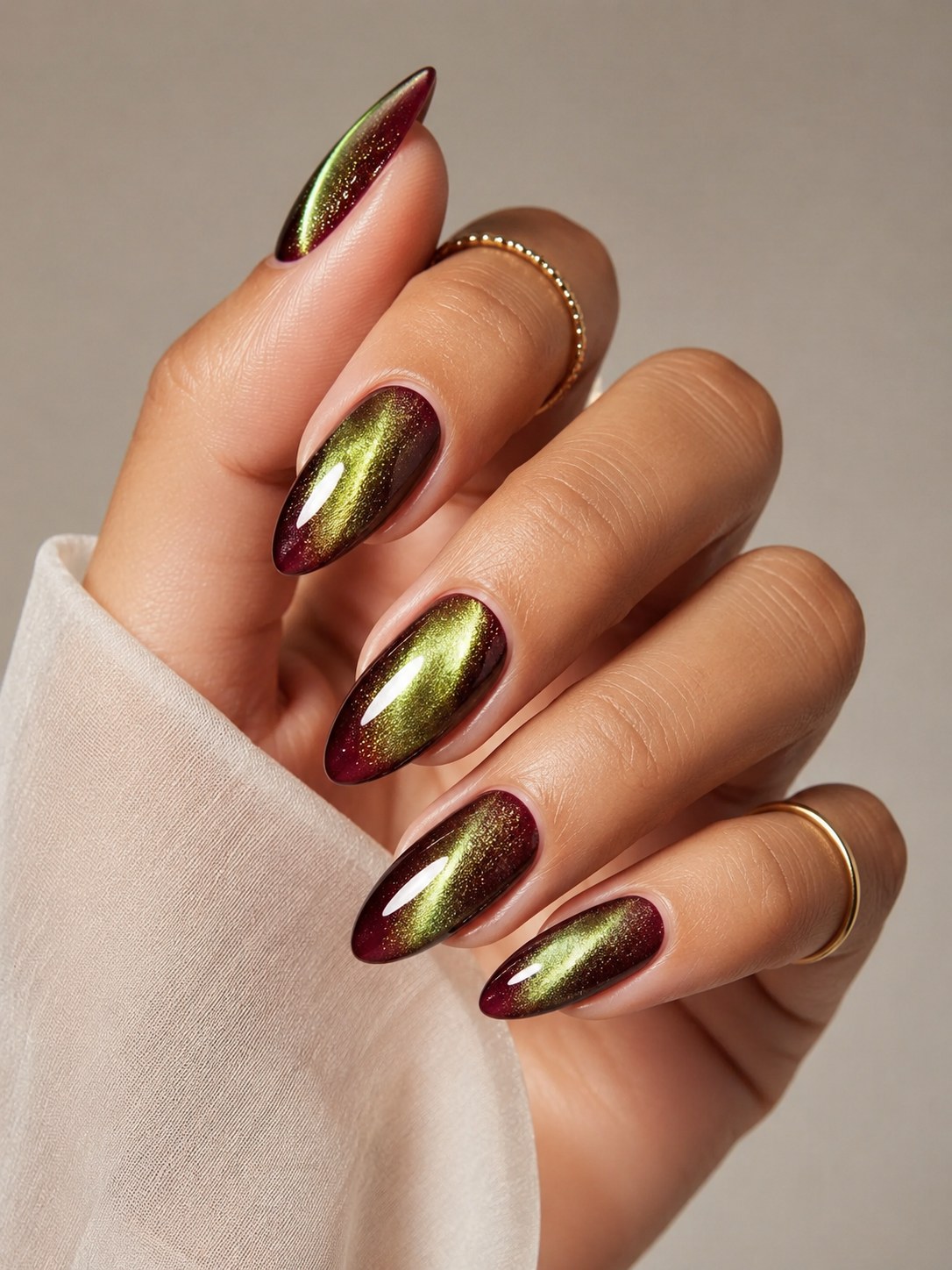 Almond nails in a burgundy-to-gold magnetic cat-eye chrome finish