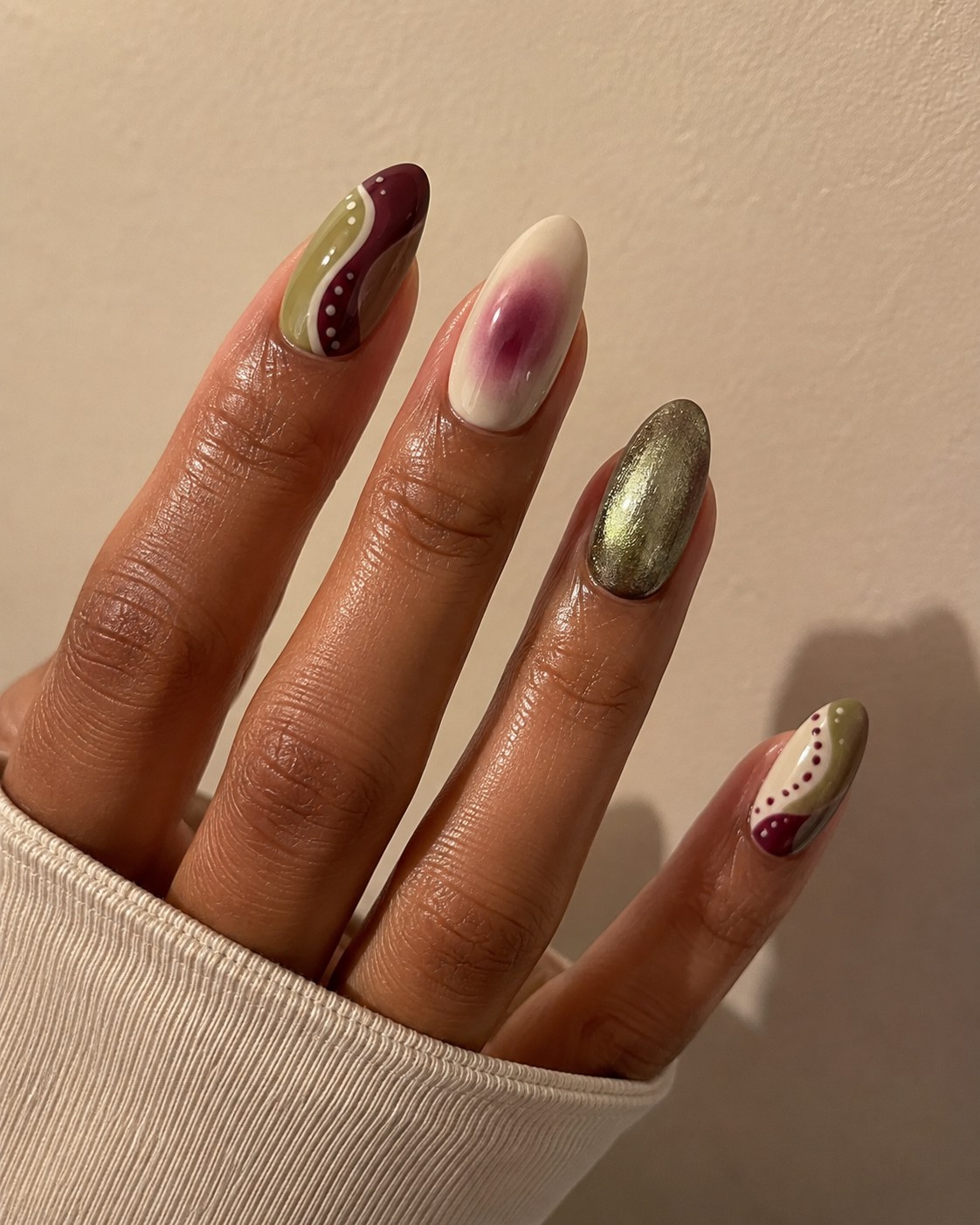 Abstract swirl nail art in burgundy, olive and gold glitter with a soft pink cloud accent nail