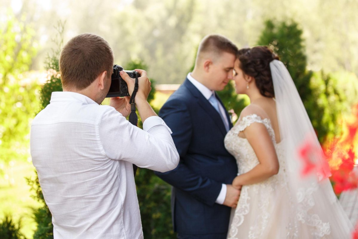 Photographer taking wedding portraits of a newly married couple outdoors